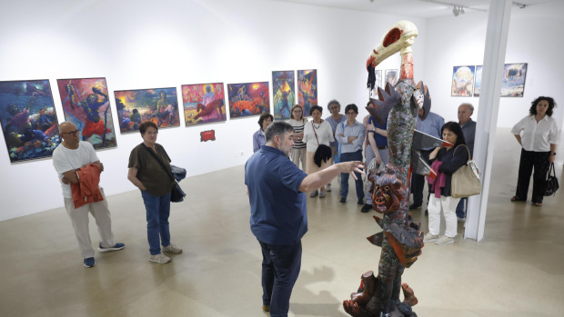 José Liñeira, responsable del centro cultural Torrente Ballester, guiando una visita a la exposición de Xoán Braxe