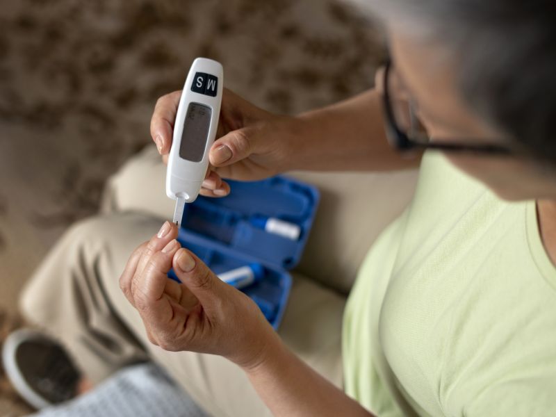 Mujer diabetica de alto angulo comprobando su nivel de glucosa