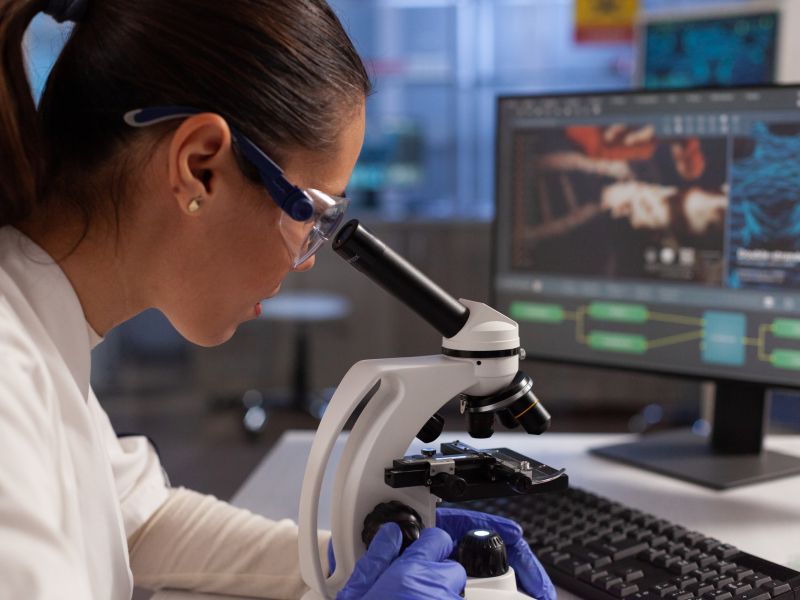 Bioquimico que trabaja en el microscopio para la ilustracion celular en la pantalla de la computadora en el laboratorio quimico mujer cientifica analizando adn del virus tejido celular diagrama de nucleo de plasma y hemoglobina
