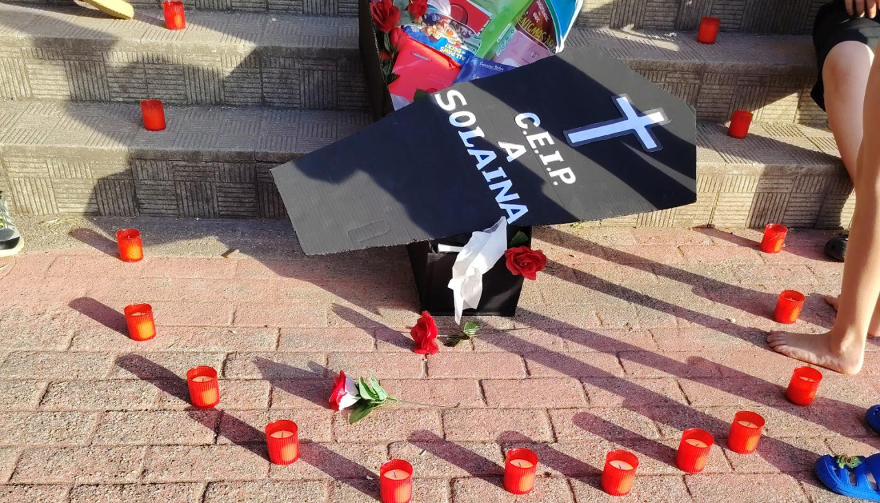 Ataúd con libros y velas encendidas en la concentración