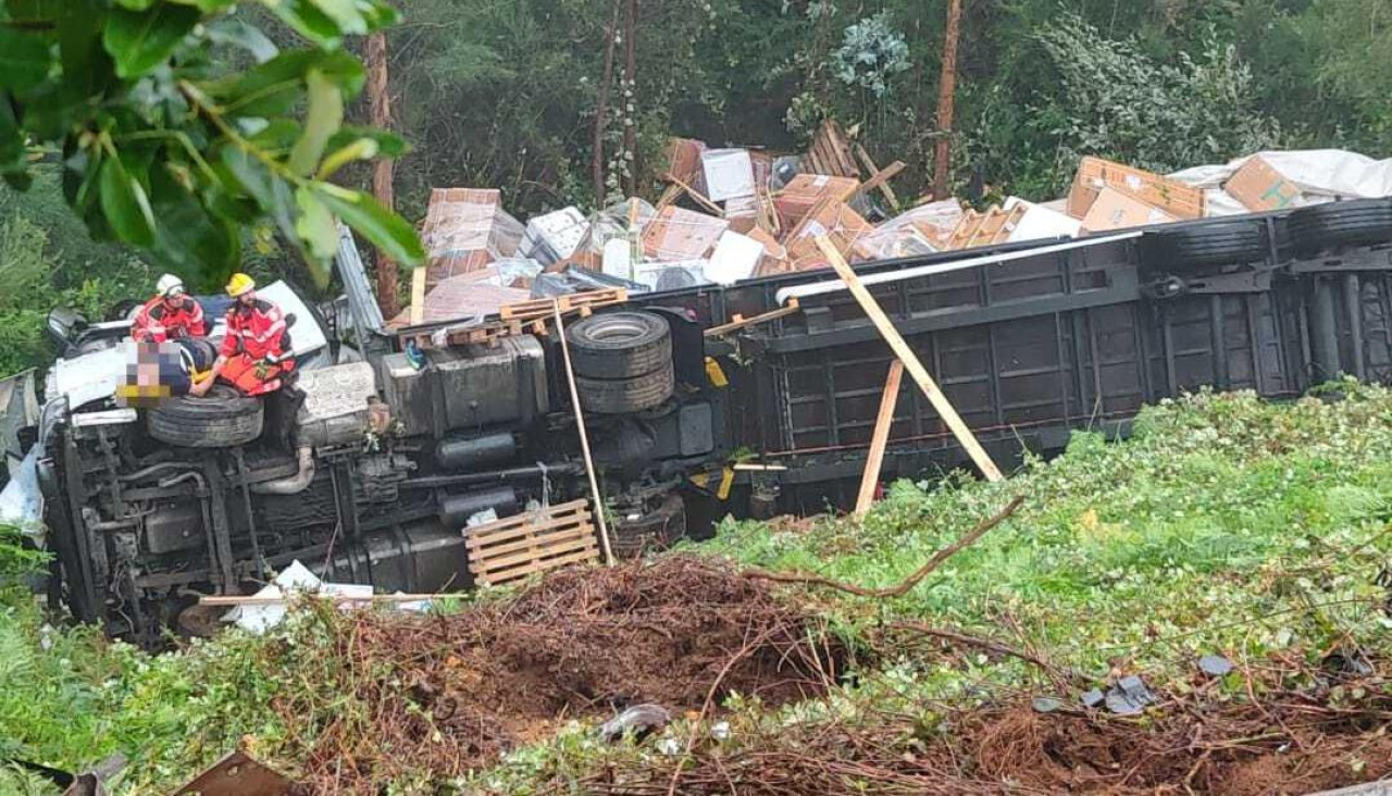 El tráiler quedó tumbado de costado, mientras que los equipos de emergencias atendían al camionero