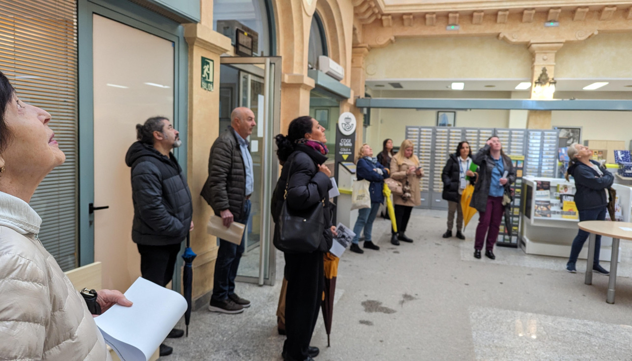 Participantes mirando el techo de vidriera en la visita a Correos del pasado 2025, por la Semana do Patrimonio Invisible