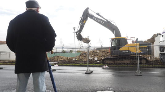 Un vecino observando a los trabajadores retirar el muro defensivo con una excavadora